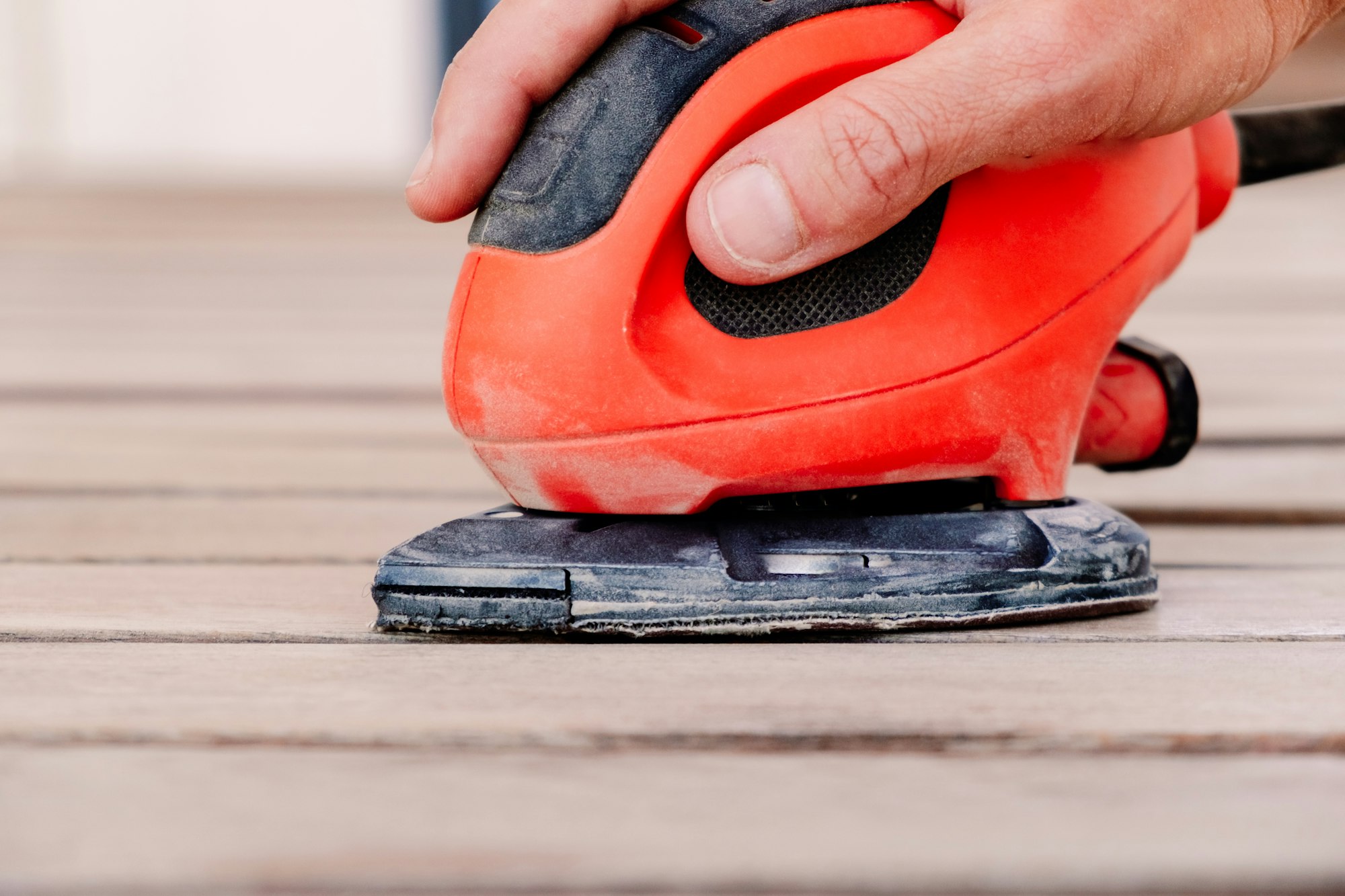 A hand held wood sander held by a woman.