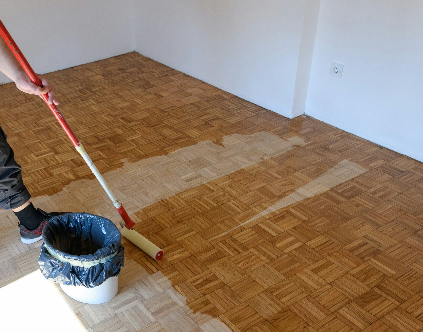 Man applying lacquer finish on oak hardwood floor