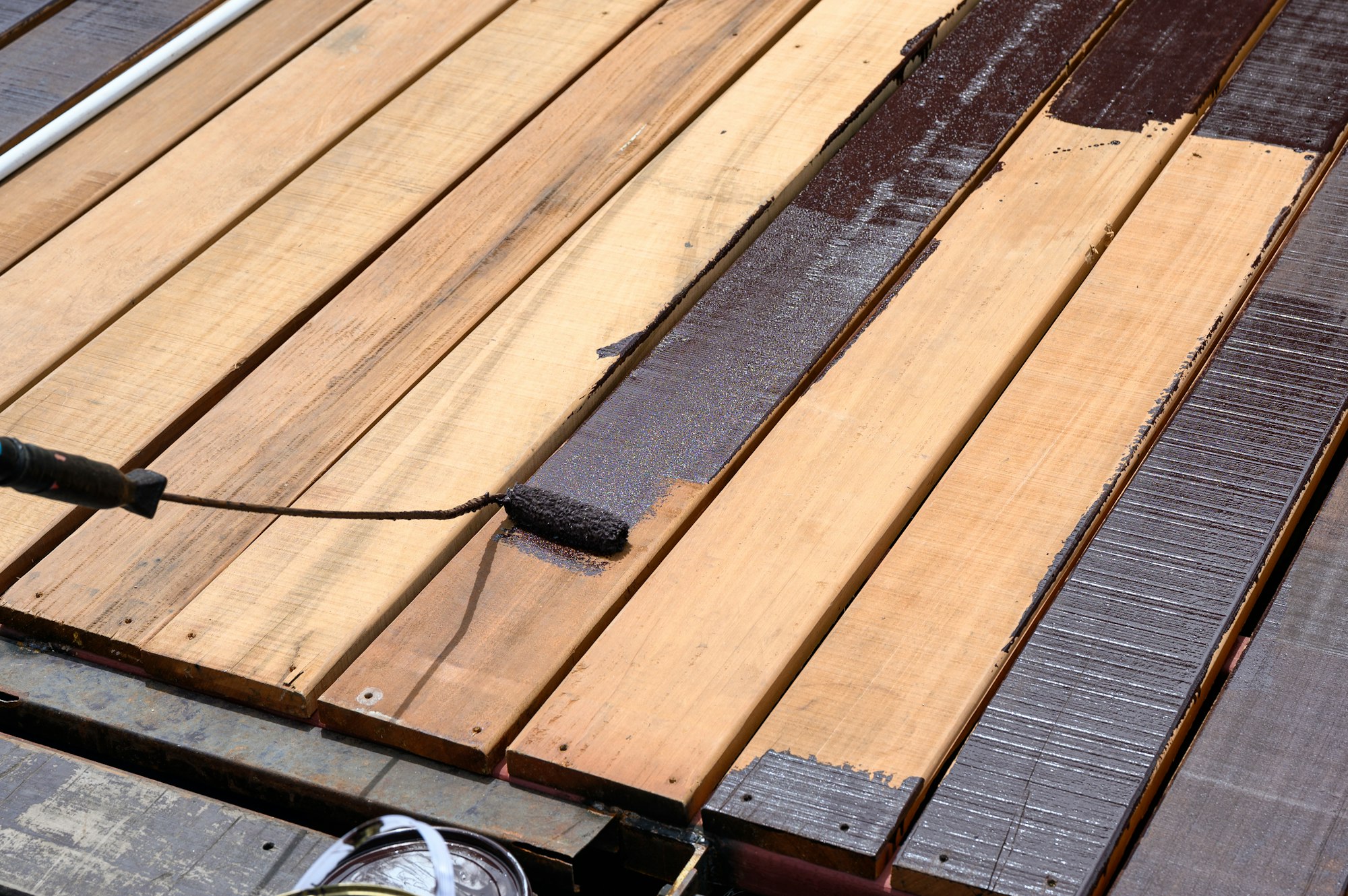 Worker painting with paint roller on wood floor