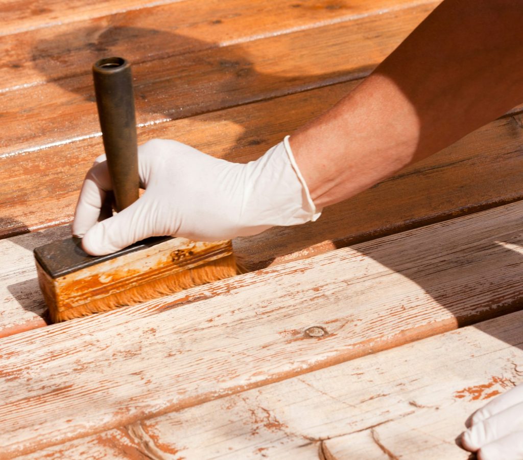 Deck maintenance apply stain on wooden decking