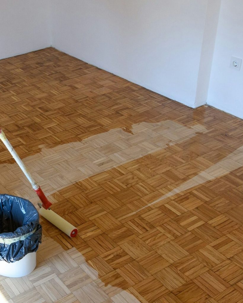 Man applying lacquer finish on oak hardwood floor